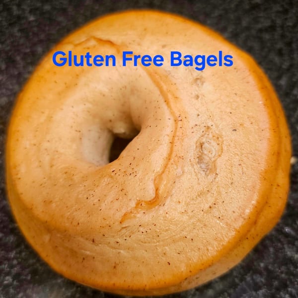 A close-up of a golden-brown gluten-free bagel from Bagels N' Cream, with "Gluten Free Bagels" text overlay.