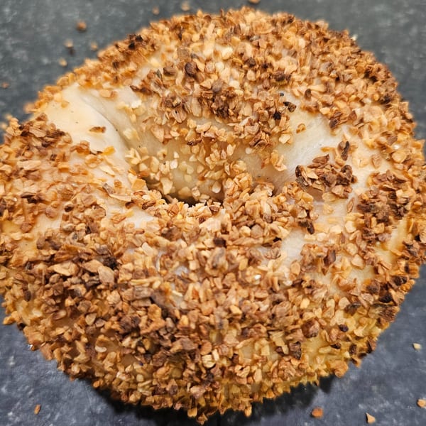 Close-up of a golden-brown bagel from Bagels N' Cream, generously topped with toasted garlic flakes.