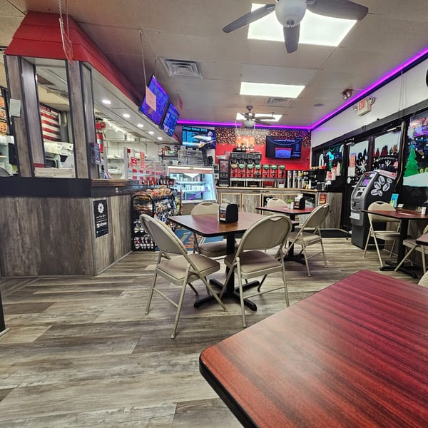 Interior of Bagels N' Cream, showing dining tables, a service counter, and coffee machines.