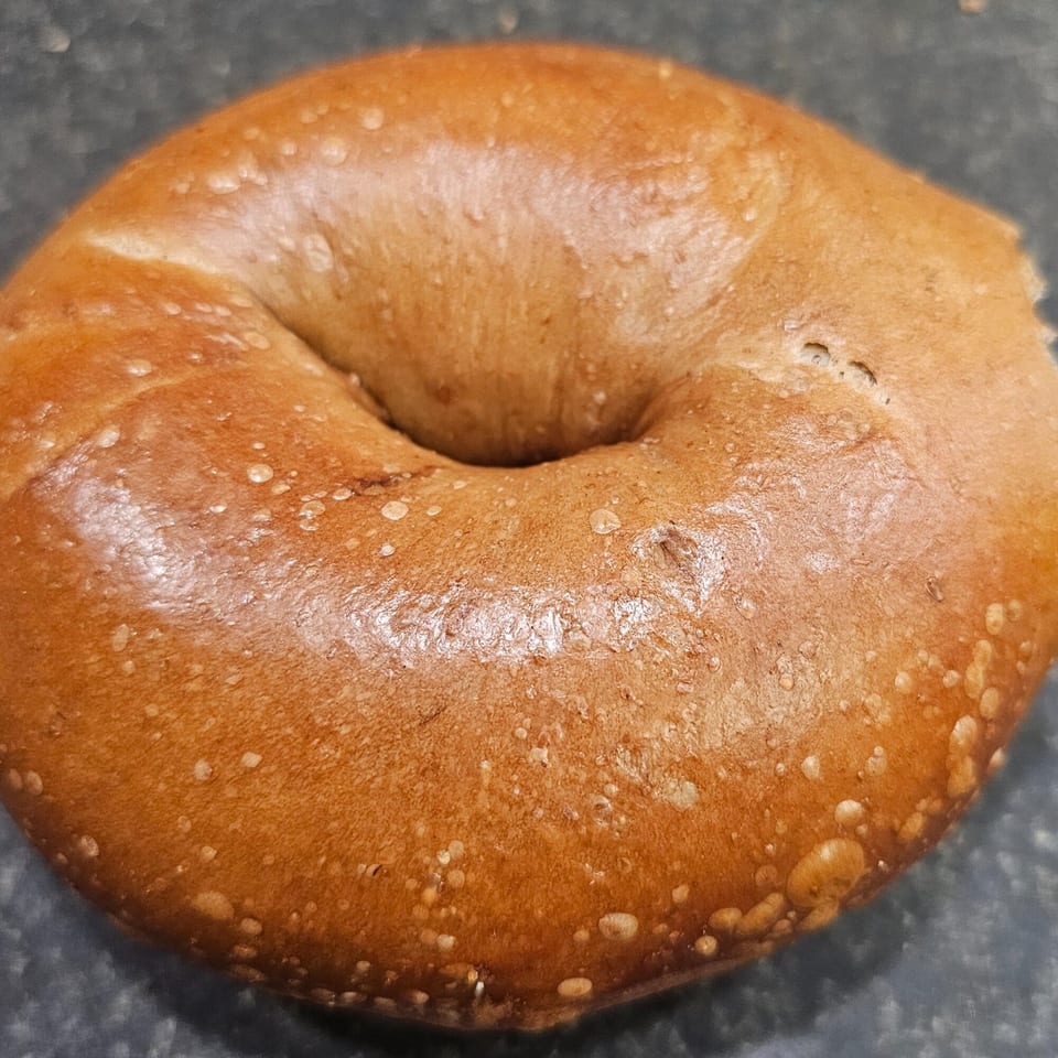 A freshly baked, golden-brown bagel from Bagels N' Cream, ready to be enjoyed.