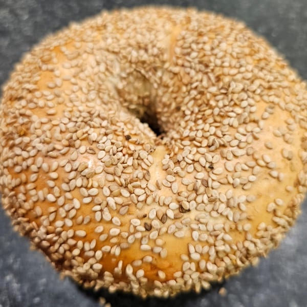 A close-up, top-down view of a golden-brown sesame bagel from Bagels N' Cream.