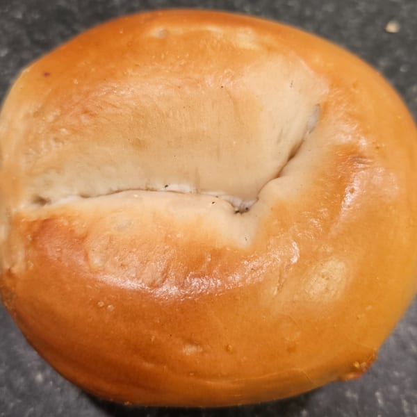 A close-up of a freshly baked, golden-brown bagel from Bagels N' Cream.