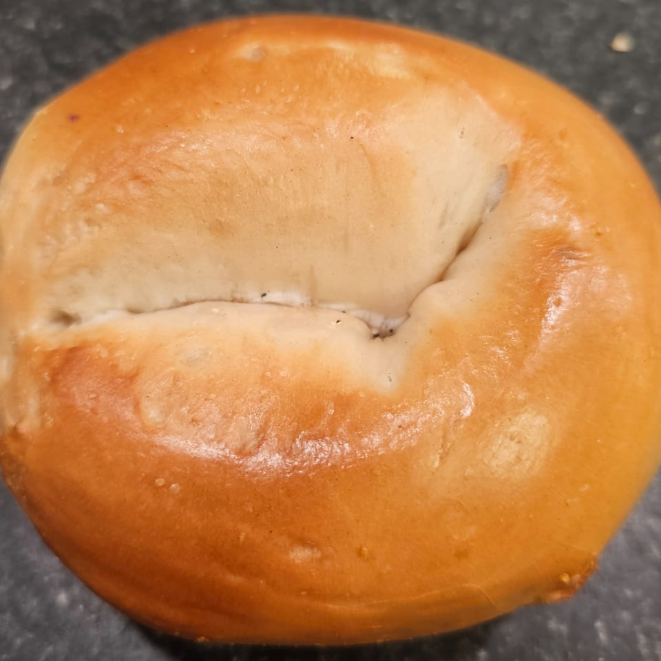 A close-up of a freshly baked, golden-brown bagel from Bagels N' Cream.