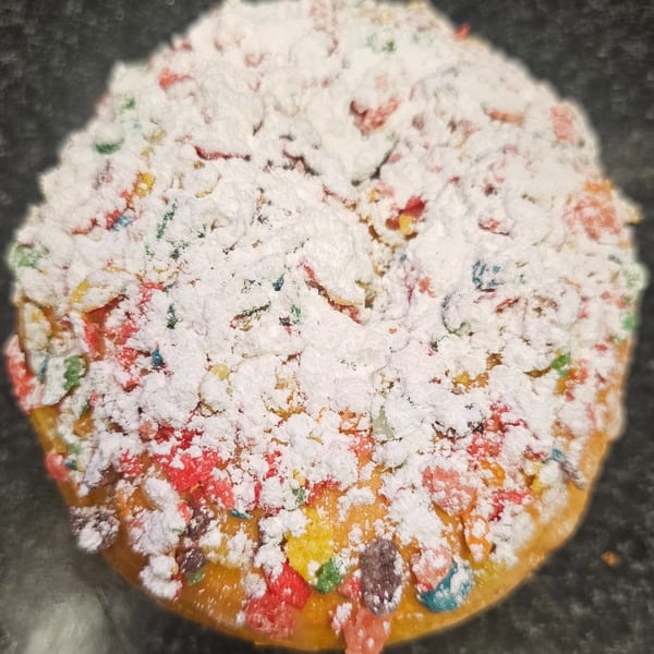 A Bagels N' Cream bagel topped with colorful cereal pieces and powdered sugar.