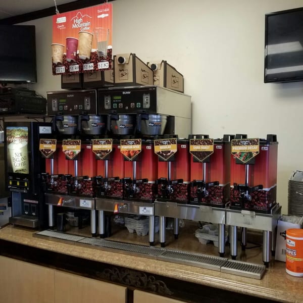A self-serve coffee station at Bagels N' Cream with multiple coffee dispensers and flavor options.