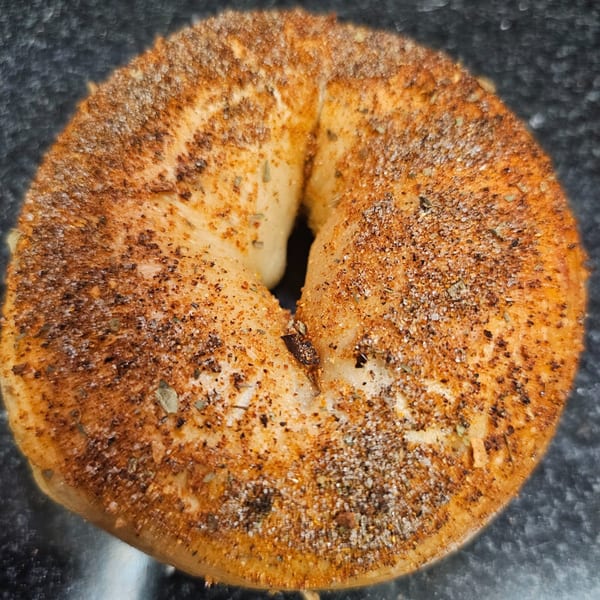 A close-up of a Bagels N' Cream bagel, generously topped with everything seasoning.