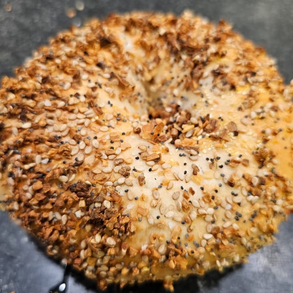 Close-up of an everything bagel from Bagels N' Cream, topped with seeds and garlic.