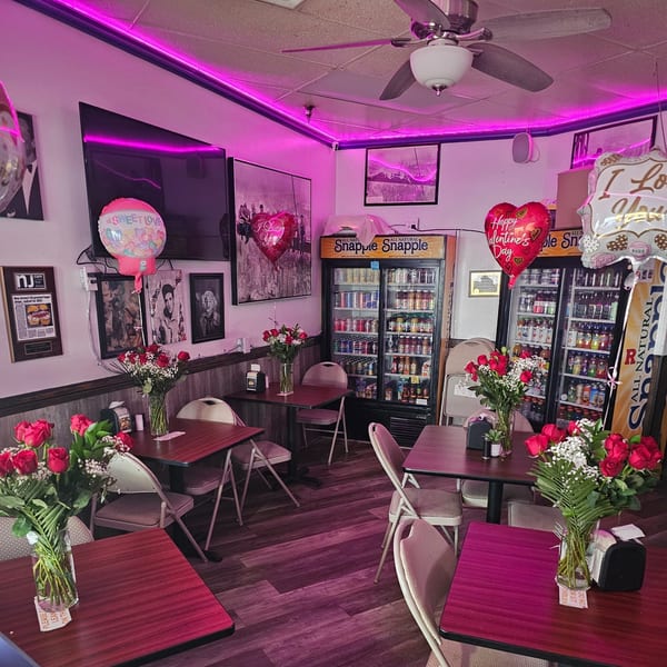 Bagels N' Cream dining area decorated with red roses, balloons, and pink neon lights for Valentine's Day.