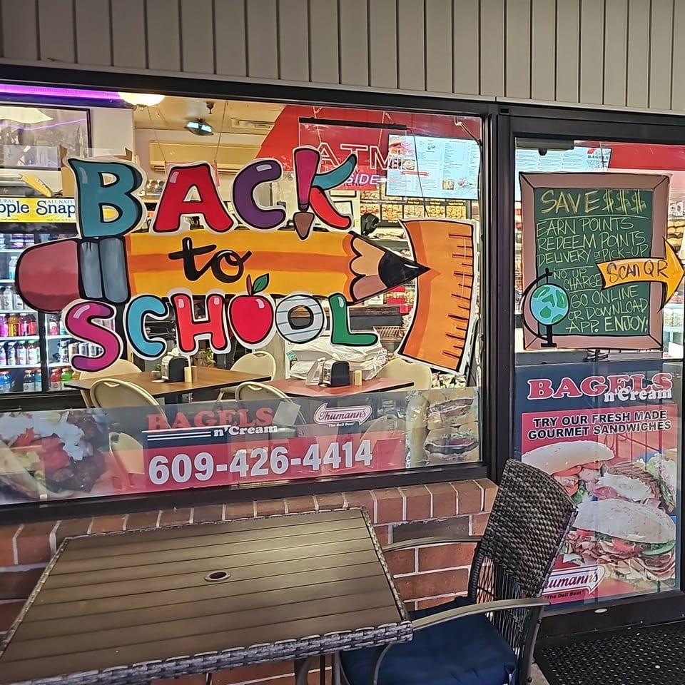 Bagels N' Cream storefront window with a colorful "Back to School" sign and promotional posters.