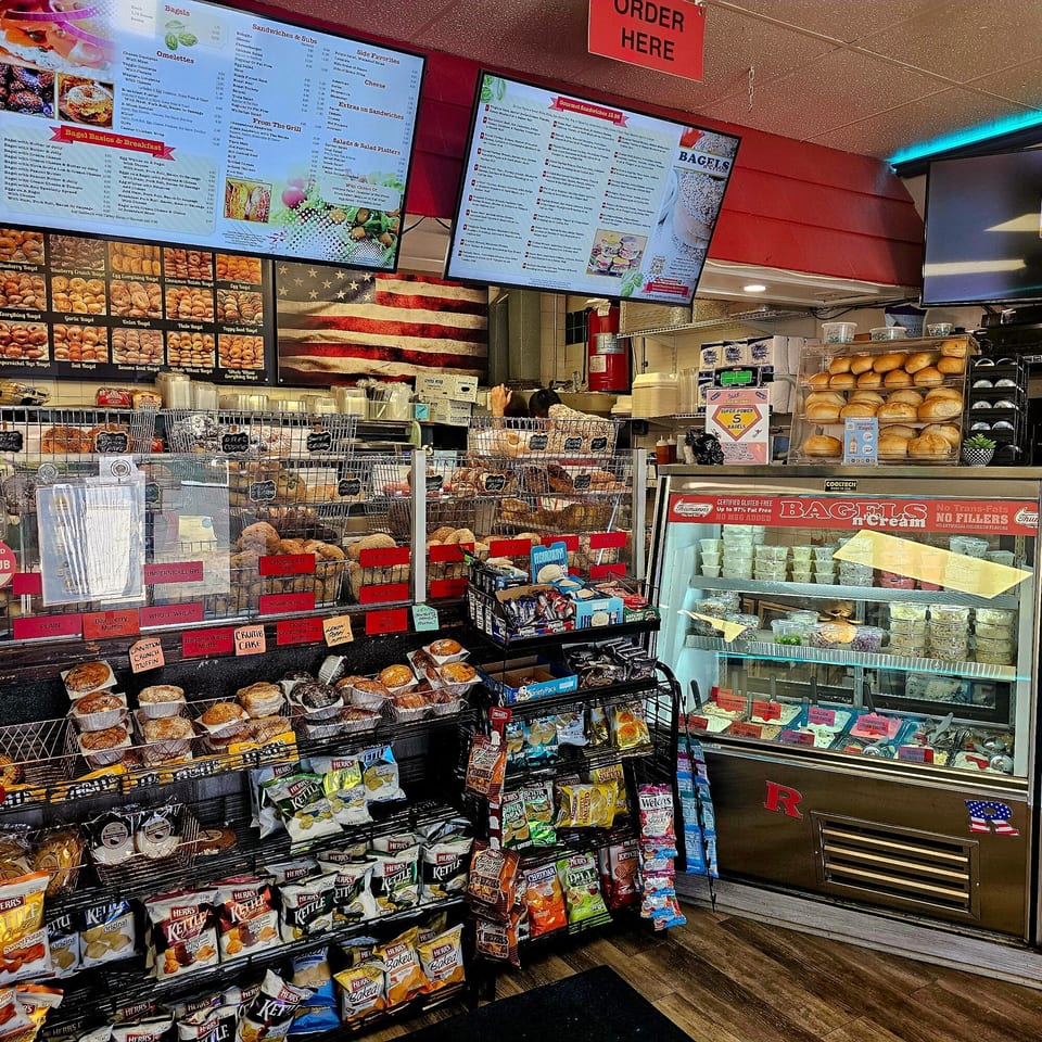 A wide shot of the Bagels N' Cream interior, showcasing various bagels, muffins, chips, and cream cheeses.