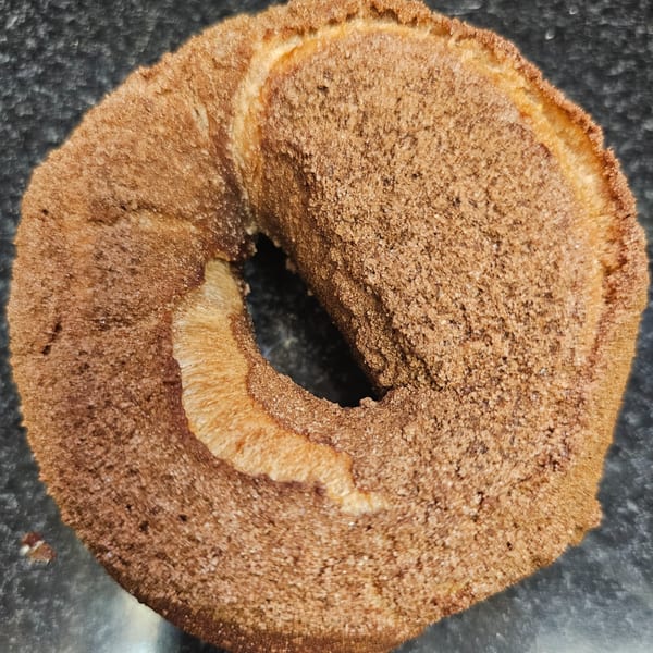 A cinnamon sugar bagel from Bagels N' Cream, close-up on a dark surface.