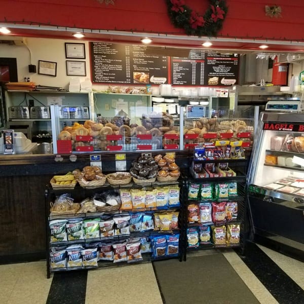 Interior view of Bagels N' Cream, showing display cases filled with bagels, snacks, and a menu board.