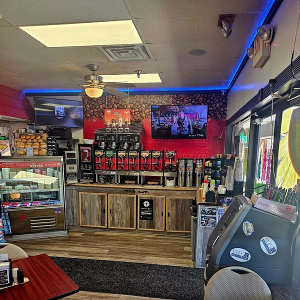 Interior of Bagels N' Cream with a coffee station, bagel display, and red accent wall.