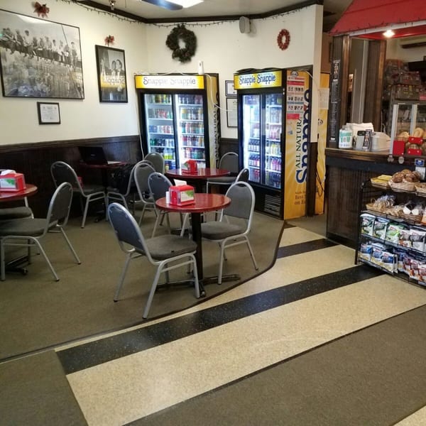 Interior of Bagels N' Cream with red tables, gray chairs, Snapple refrigerators, and a bagel counter.
