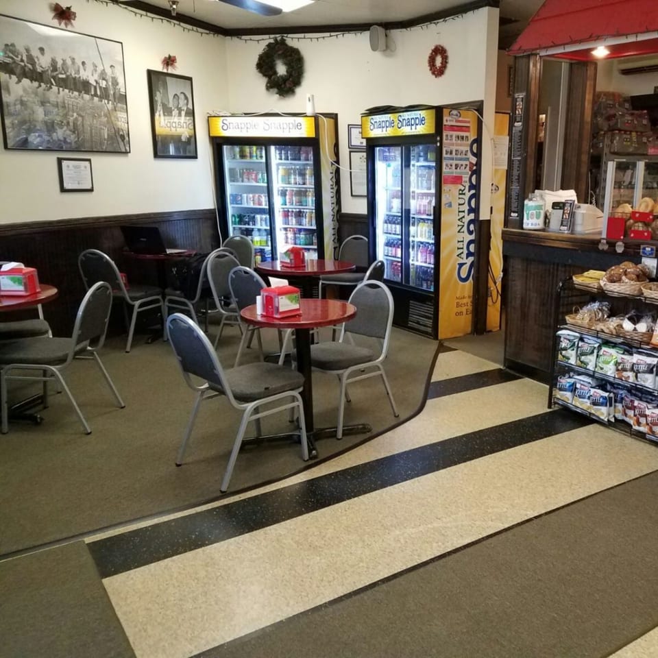 Interior of Bagels N' Cream with red tables, gray chairs, Snapple refrigerators, and a bagel counter.